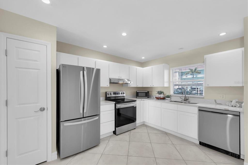 8 Glencoe Place, Unit 105 Dunedin, FL 34698 - Photo 8 of 44 a kitchen with a refrigerator a sink and white cabinets