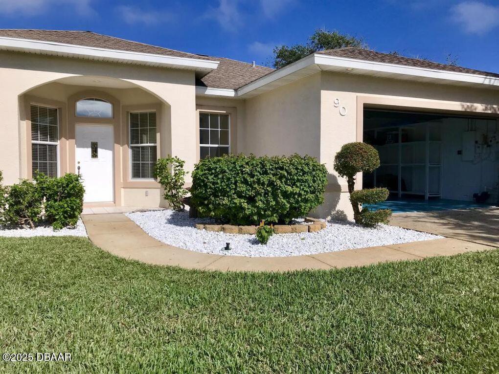 90 Buschman Drive Ponce Inlet, FL 32127 - Photo 2 of 37 a front view of a house with garden