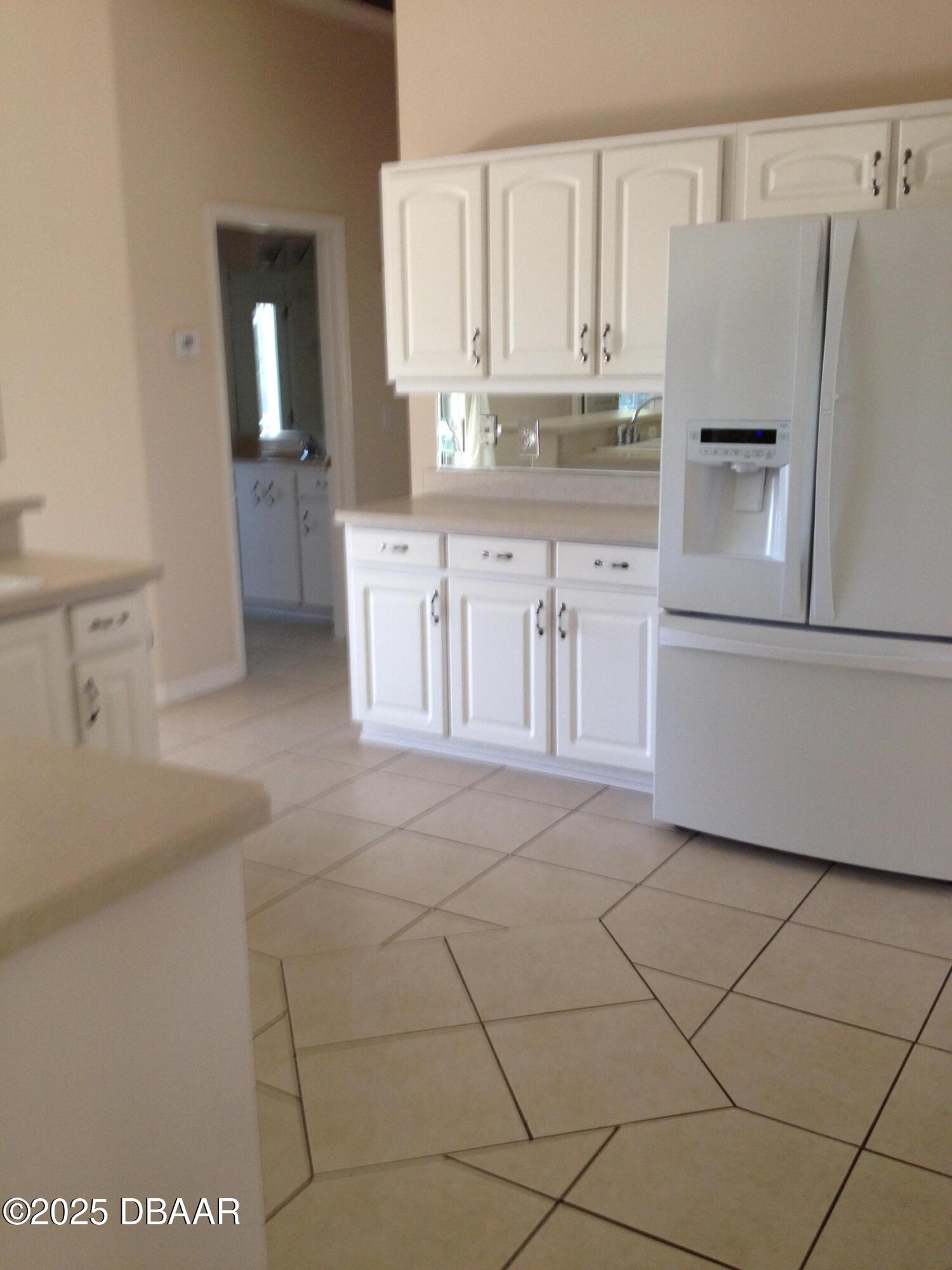 90 Buschman Drive Ponce Inlet, FL 32127 - Photo 7 of 37 a kitchen with granite countertop white cabinets and refrigerator