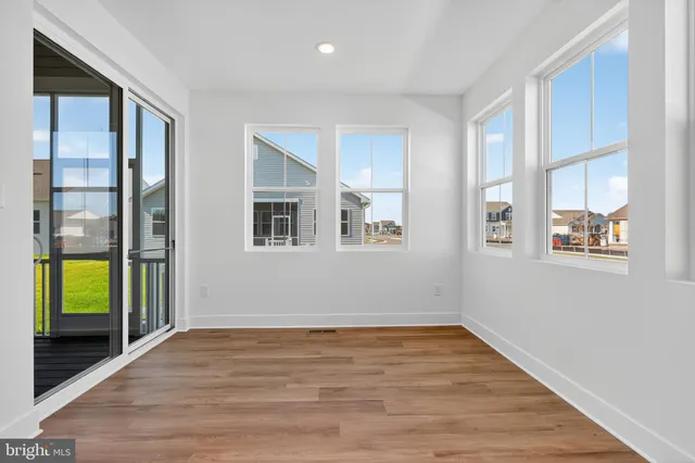 a view of an empty room with window and wooden floor