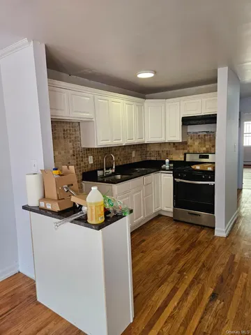 a view of kitchen and empty room with wooden floor