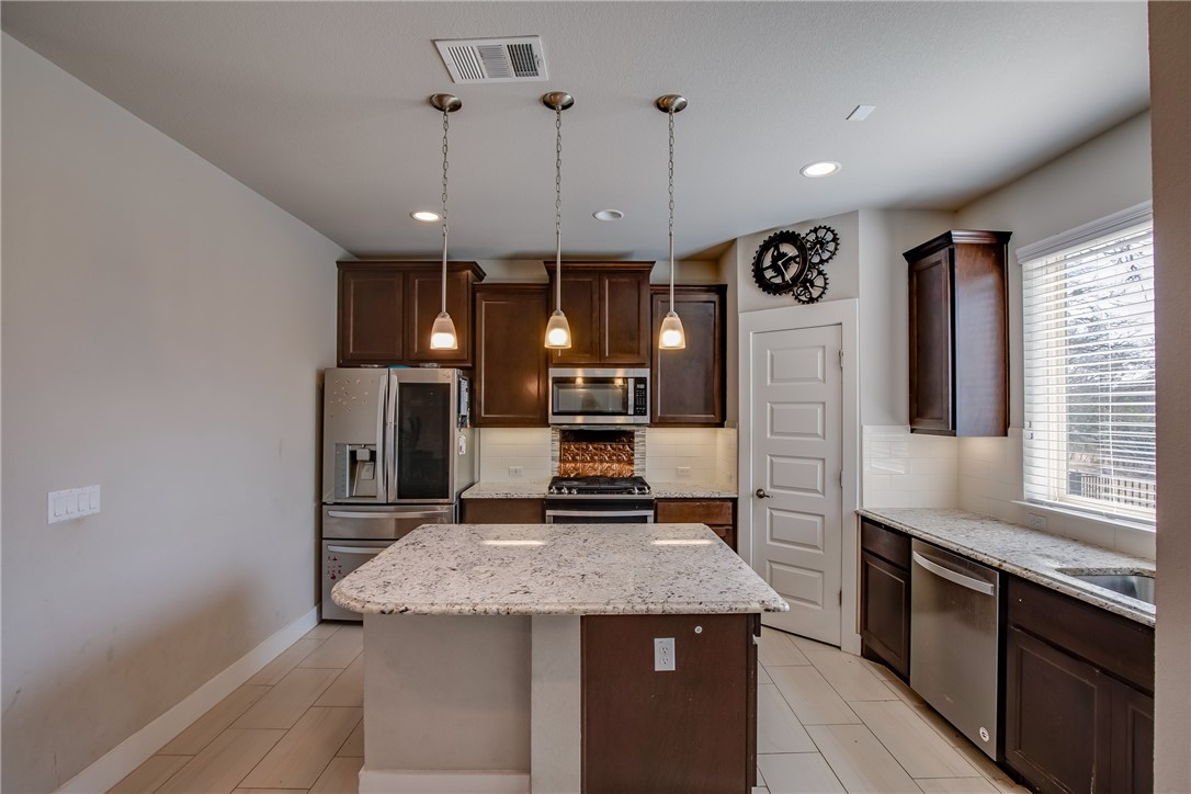9707 McKnight Loop Austin, TX 78717 - Photo 6 of 17 a kitchen with stainless steel appliances granite countertop a sink a stove and a refrigerator
