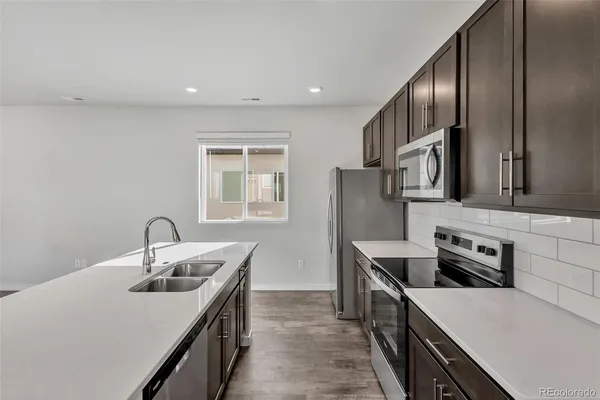 a kitchen with stainless steel appliances granite countertop a sink stove and refrigerator