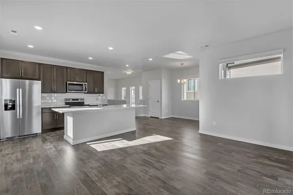 a large kitchen with kitchen island a sink dishwasher a refrigerator and a stove with wooden floor