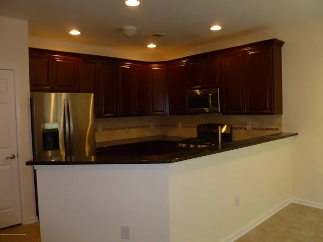 a view of kitchen with stainless steel appliances wooden cabinets and a refrigerator