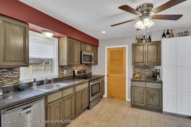 a kitchen with granite countertop a sink stainless steel appliances and cabinets