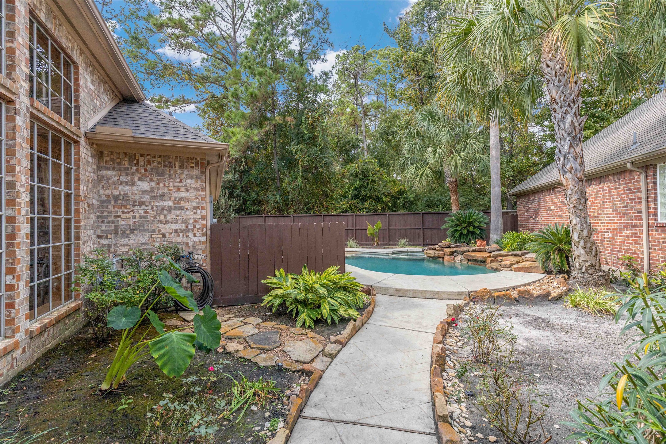 7 North Spring Brook Court Spring, TX 77382 - Photo 3 of 49 Behind a rod iron gate is your backyard oasis - trees, flowers, and a private pool with a hot tub and water feature.