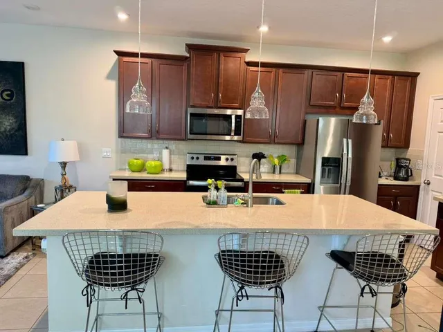 a kitchen with stainless steel appliances kitchen island granite countertop a kitchen island a stove a kitchen island a table and chairs