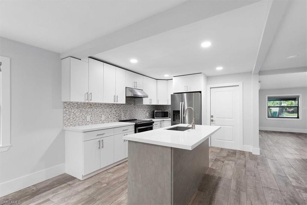3240 Collee Court Naples, FL 34112 - Photo 17 of 42 a kitchen with a sink a stove a refrigerator and white cabinets