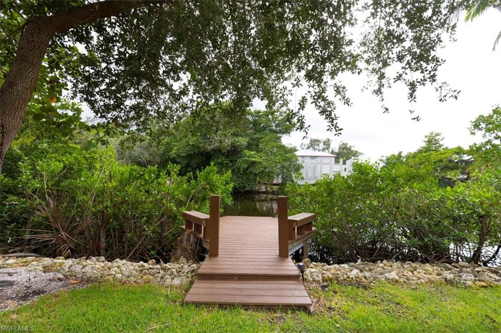 3240 Collee Court Naples, FL 34112 - Photo 29 of 42 a view of a fountain in front of a house with plants and large trees