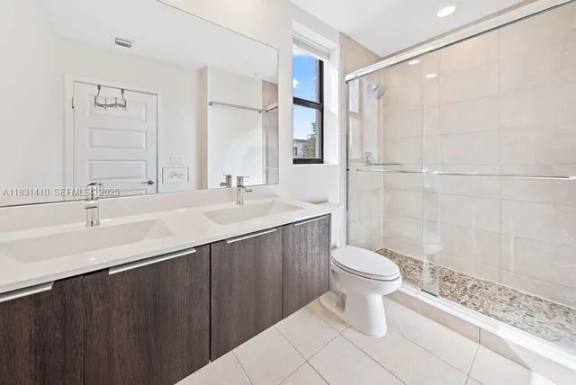 a bathroom with a sink a toilet a mirror and shower