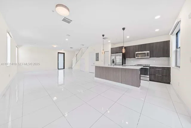 a open kitchen with stainless steel appliances kitchen island granite countertop a refrigerator and a sink