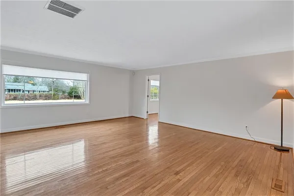 an empty room with wooden floor cabinet and windows