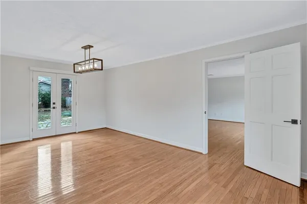 a view of an empty room with wooden floor and windows