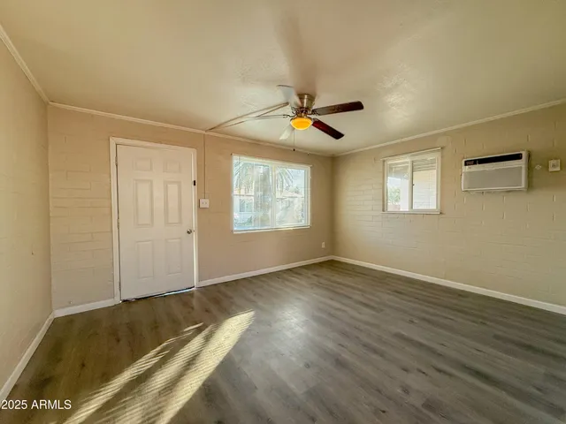 a view of empty room with wooden floor and fan