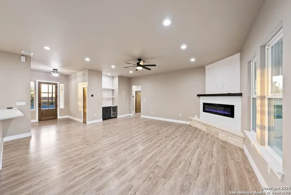 a view of an empty room with wooden floor and a kitchen
