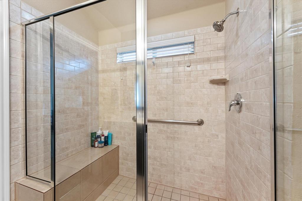 409 Harding Lane Lavon, TX 75166 - Photo 13 of 34 Enclosed shower featuring a built-in bench, tiled walls, tiled flooring, a chrome showerhead, and a grab bar