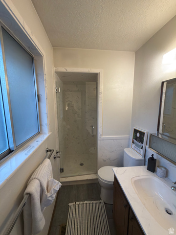 1164 East Mountain Road Logan, UT 84321 - Photo 43 of 45 Bathroom featuring a glass-enclosed standing shower with white-patterned wall panels, a wood-finish vanity with an integrated sink and white countertop, and a frosted window