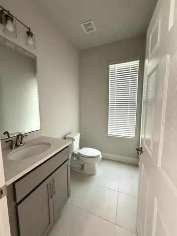 a bathroom with a granite countertop sink toilet a mirror and a window