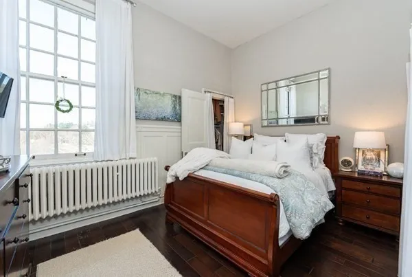 a bedroom with a bed and a window with wooden floor