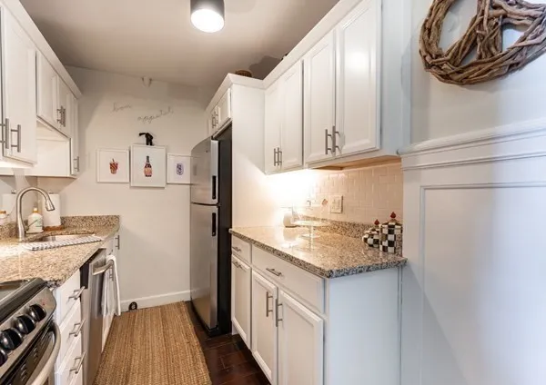 a kitchen with stainless steel appliances granite countertop a refrigerator sink and white cabinets with wooden floor