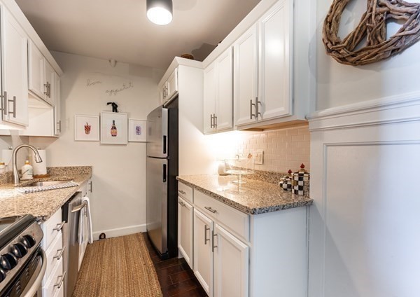 16 Balmoral Street, Unit 410 Andover, MA 01810 - Photo 8 of 34 a kitchen with stainless steel appliances granite countertop a refrigerator sink and white cabinets with wooden floor
