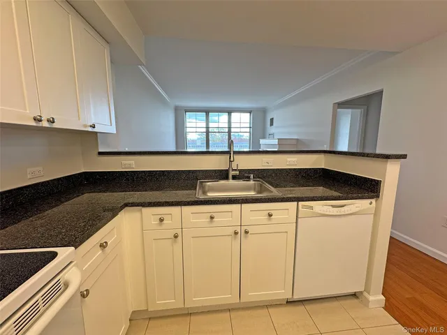 a kitchen with granite countertop white cabinets and sink