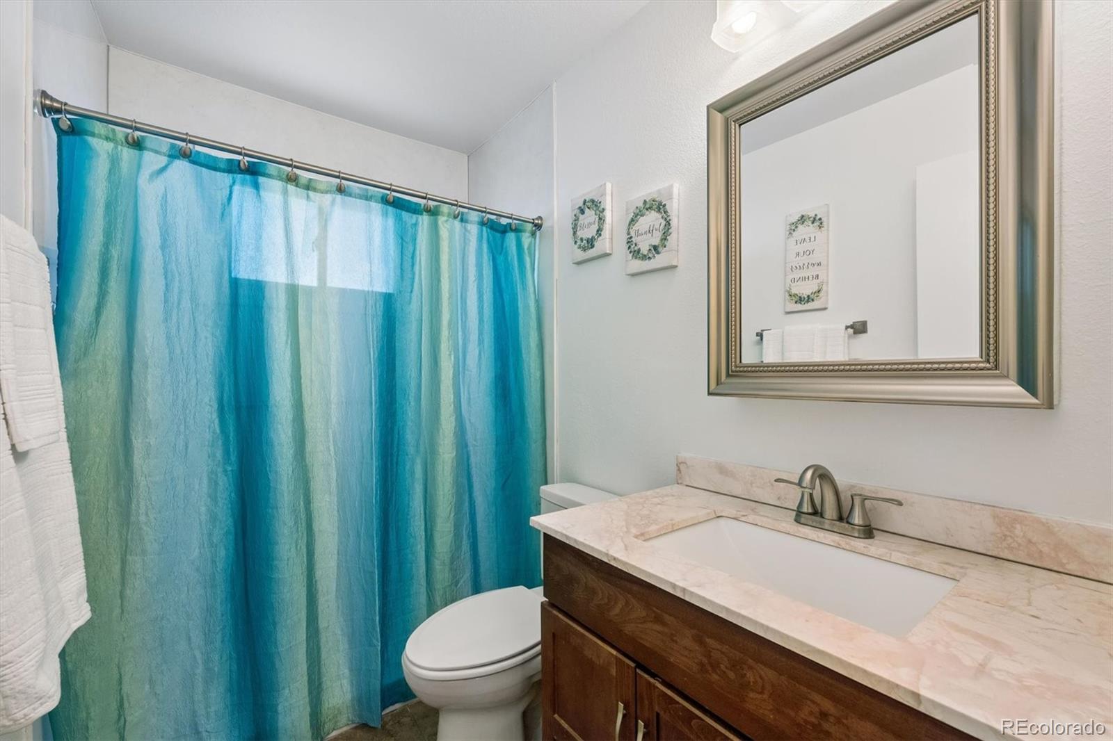 9768 Lane Street Thornton, CO 80260 - Photo 12 of 18 a bathroom with a granite countertop sink a toilet and a mirror