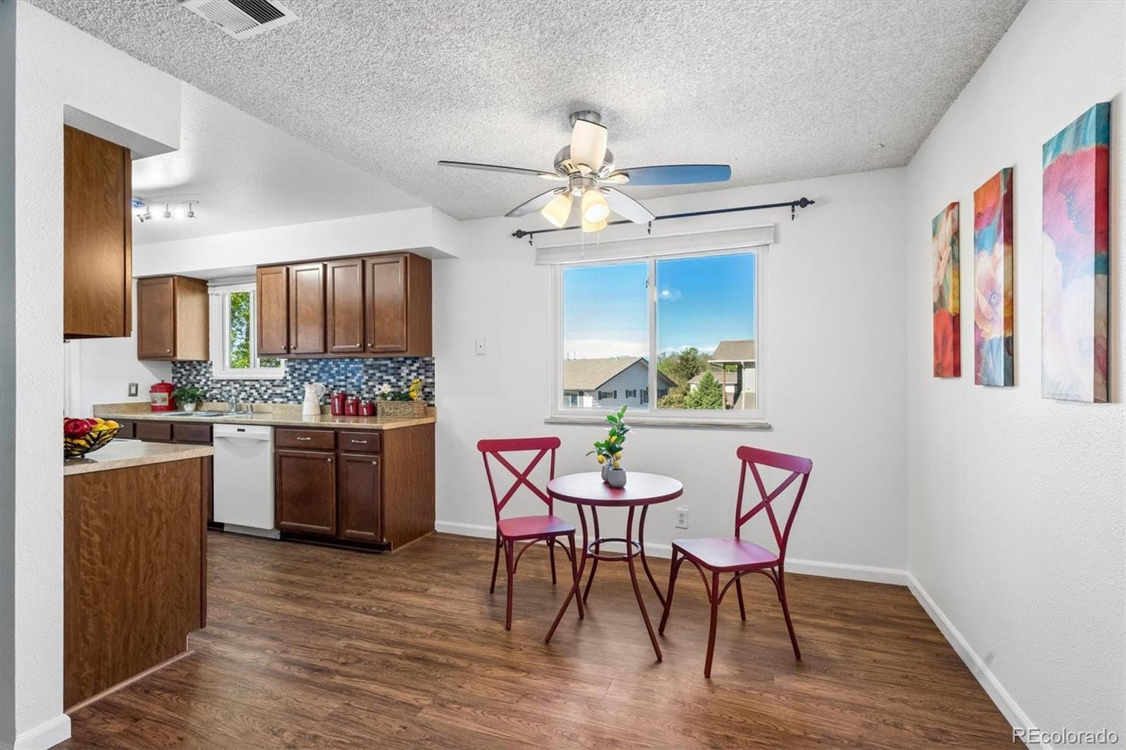 9768 Lane Street Thornton, CO 80260 - Photo 7 of 18 a kitchen with stainless steel appliances kitchen island granite countertop a dining table chairs refrigerator and sink