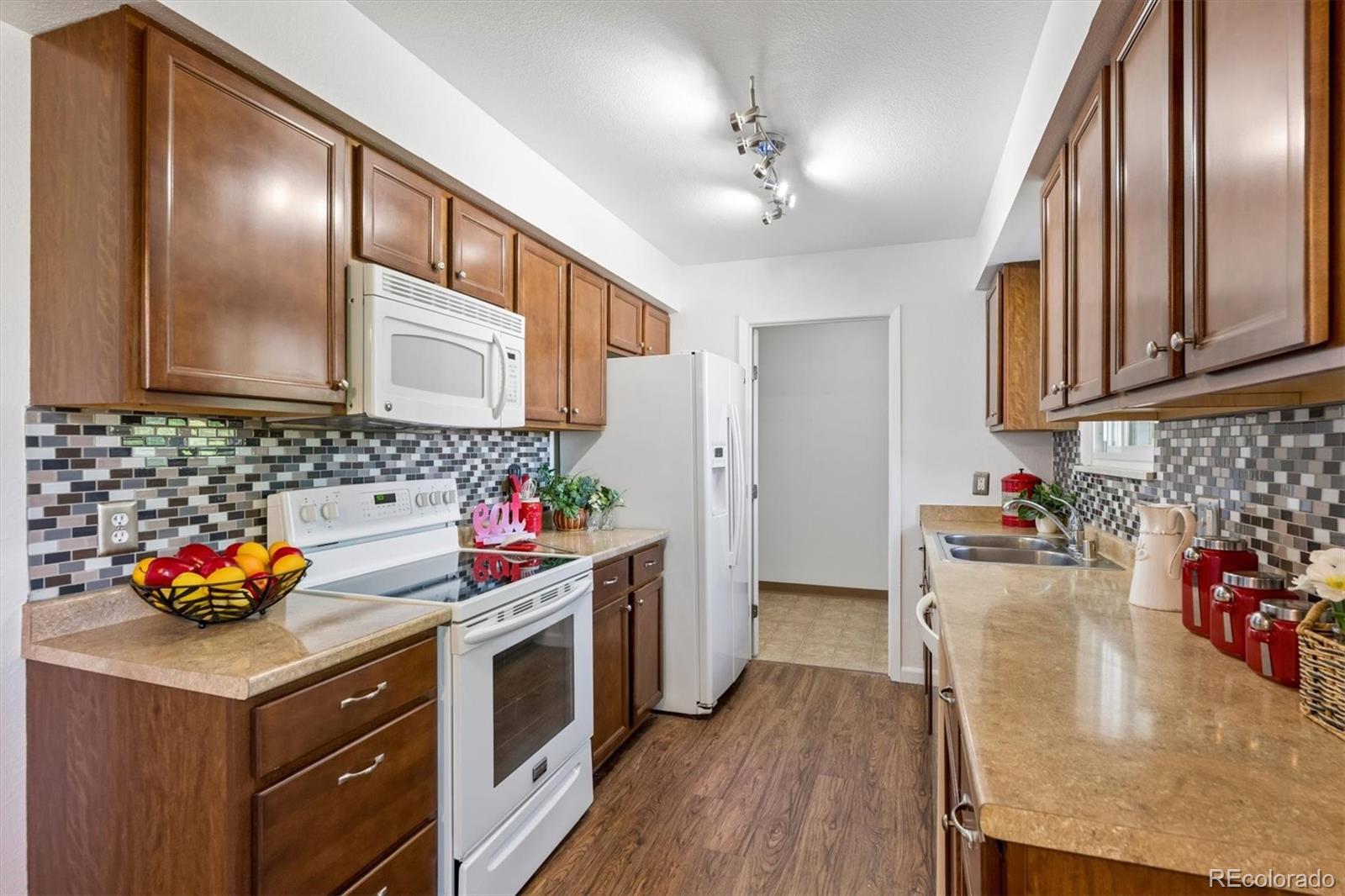 9768 Lane Street Thornton, CO 80260 - Photo 9 of 18 a kitchen with stainless steel appliances granite countertop a stove a sink dishwasher and cabinets with wooden floor