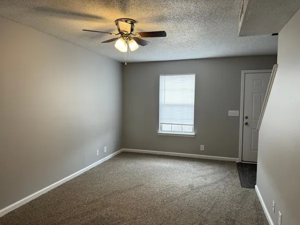 an empty room with a window and a fan