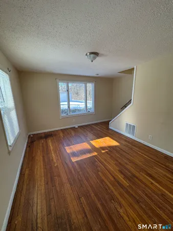 an empty room with wooden floor and windows