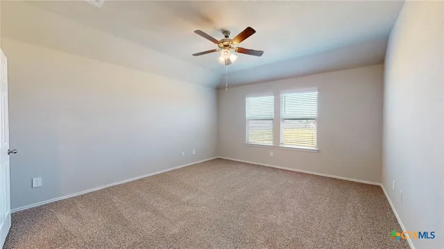 an empty room with ceiling fan and windows