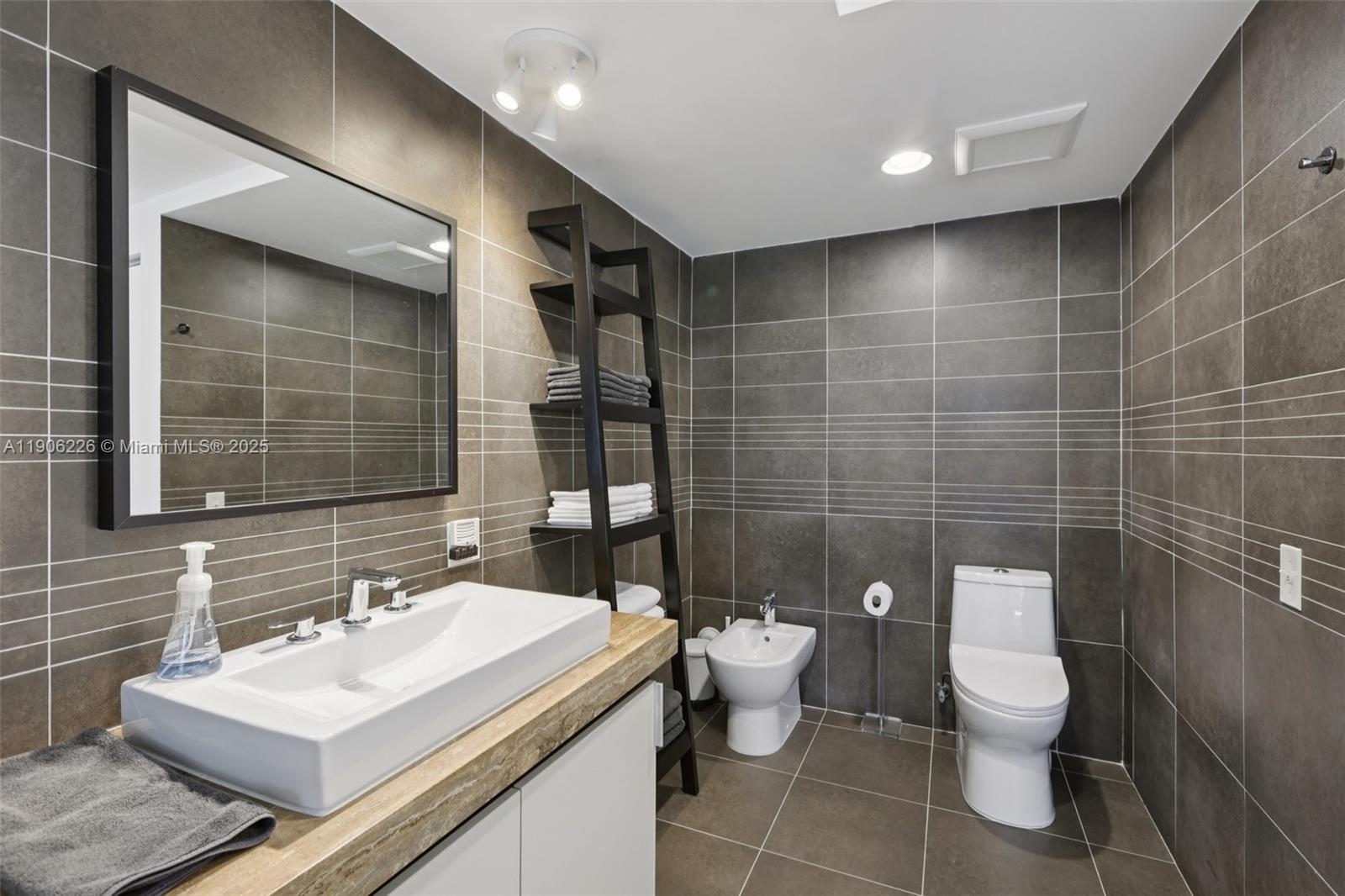 2155 Washington Court, Unit 303 Miami Beach, FL 33139 - Photo 23 of 35 a bathroom with a toilet a sink and mirror