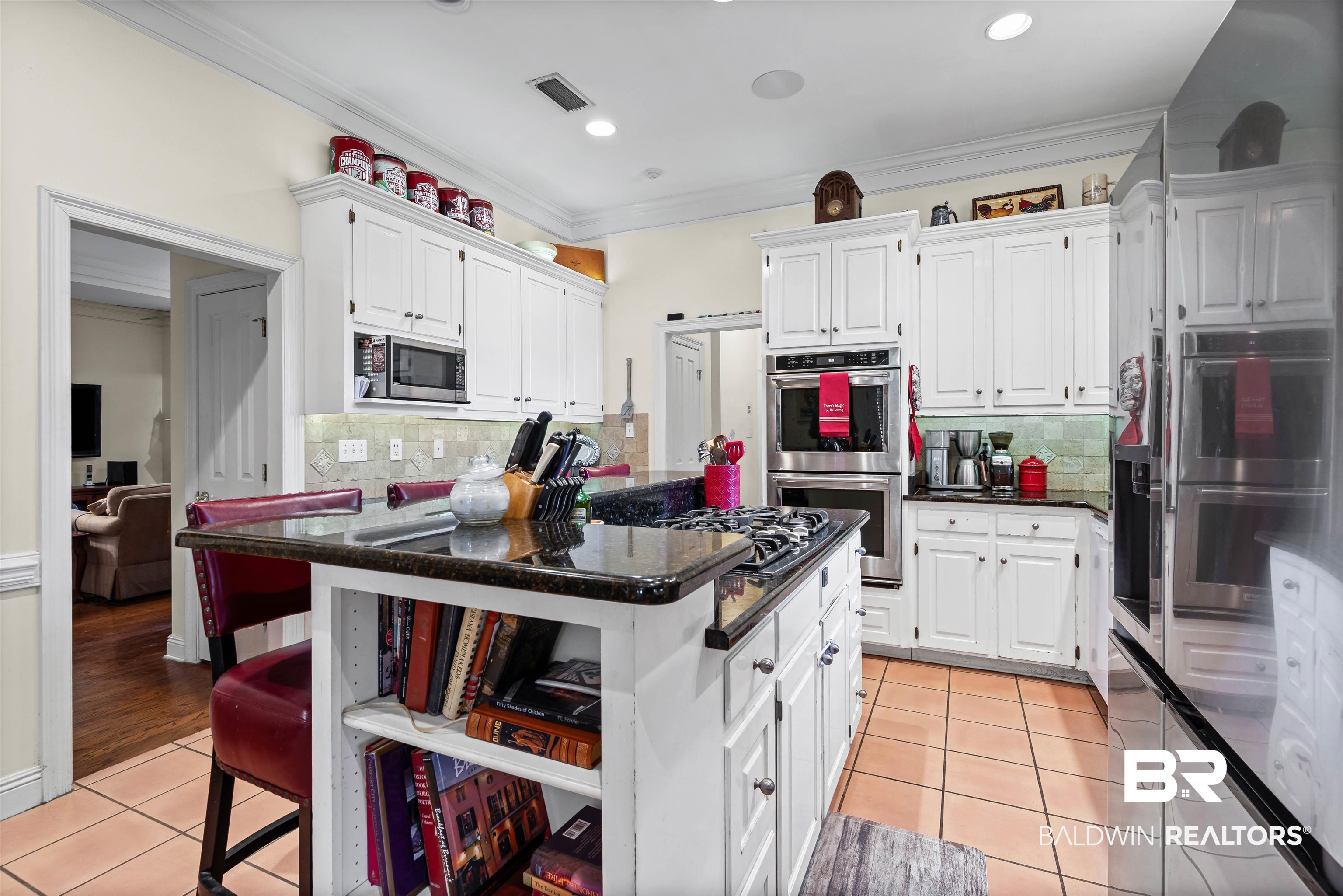 107 Beaver Dam Road Fairhope, AL 36532 - Photo 4 of 45 Kitchen with light tile patterned floors, white cabinetry, dark stone counters, a kitchen bar, and backsplash
