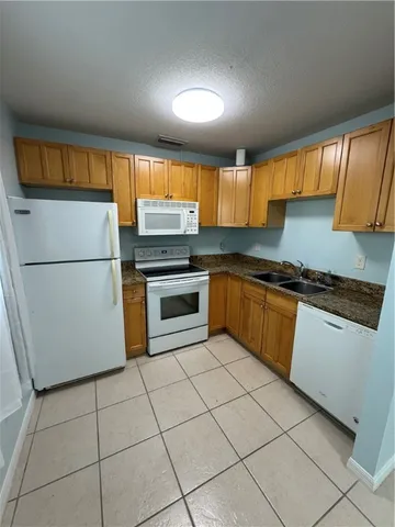 a kitchen with granite countertop a refrigerator and a stove top oven
