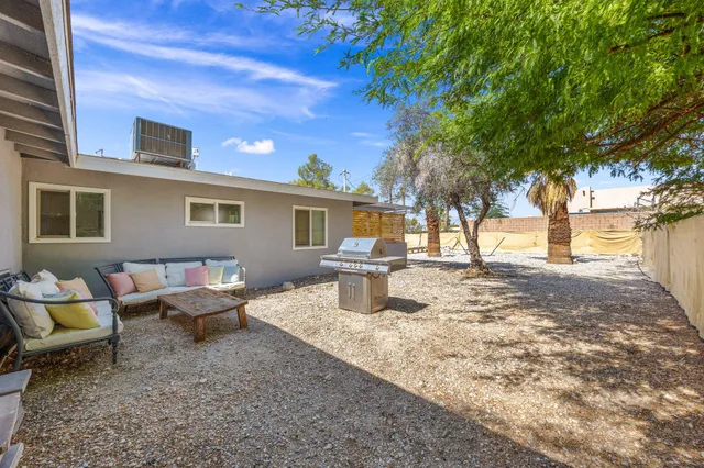 a view of a backyard with table and chairs couches under an umbrella
