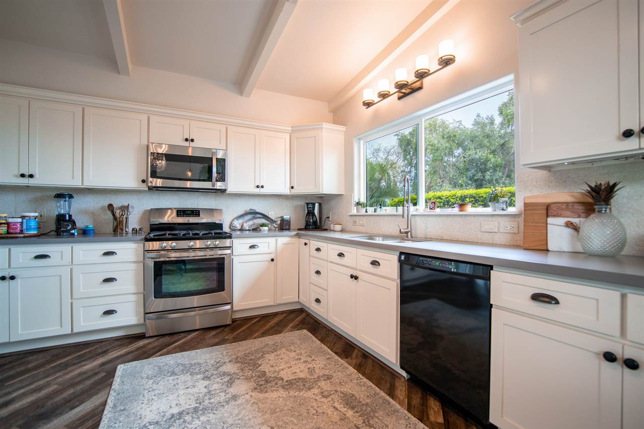 78 Ka Drive, Unit 1 Kula, HI 96790 - Photo 13 of 28 a kitchen with stainless steel appliances white cabinets a sink a stove a microwave a refrigerator and cabinets