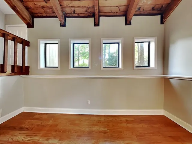 a view of an empty room with wooden floor and a window