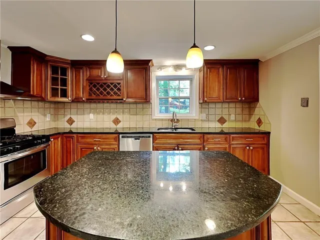 a kitchen with stainless steel appliances granite countertop a sink a stove and a wooden cabinets
