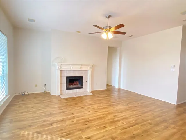 a view of an empty room with window and chandelier fan