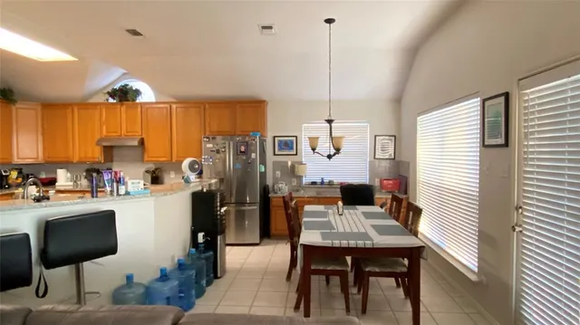 a kitchen with stainless steel appliances kitchen island granite countertop a refrigerator a stove a sink dishwasher with a dining table and chairs with wooden floor
