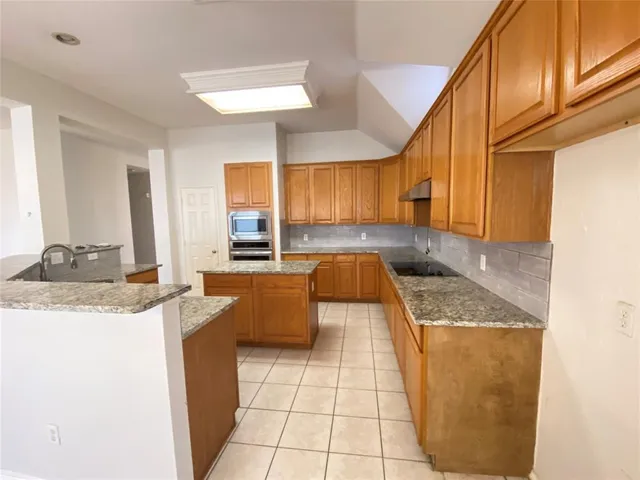 a kitchen with granite countertop a sink a stove top oven and cabinets