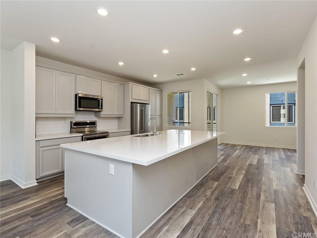 106 Citysquare Irvine, CA 92614 - Photo 1 of 21 a large kitchen with kitchen island a sink dishwasher a stove and a refrigerator with wooden floor