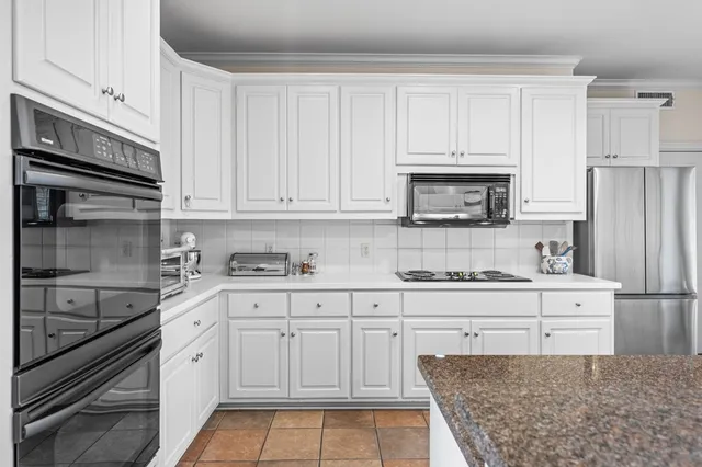 a kitchen with granite countertop white cabinets and stainless steel appliances