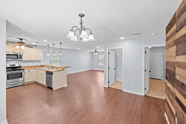 a large kitchen with granite countertop a large counter top a sink stainless steel appliances and cabinets