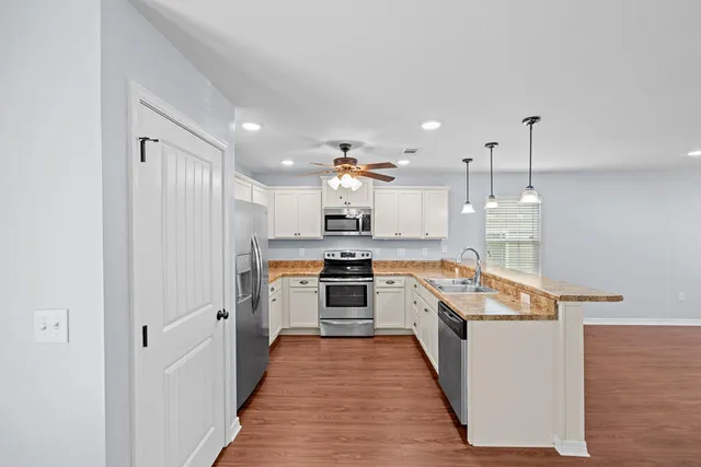 a large kitchen with stainless steel appliances granite countertop lots of counter top space and wooden floor