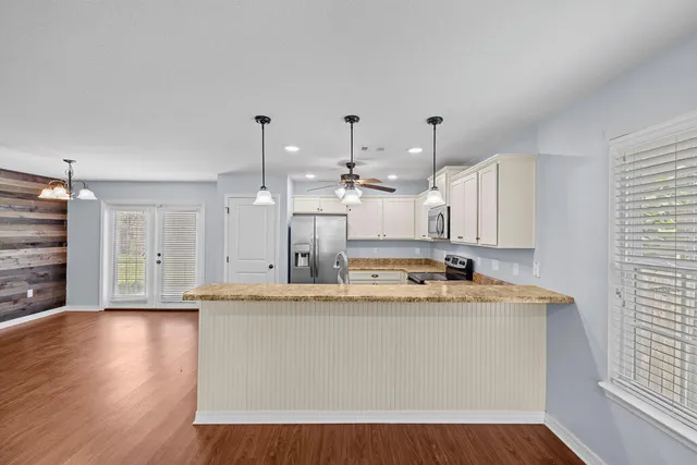 a view of a kitchen with kitchen island a sink wooden floor and counter top space