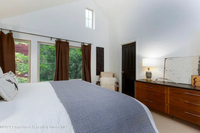 a bedroom with a large bed and large windows