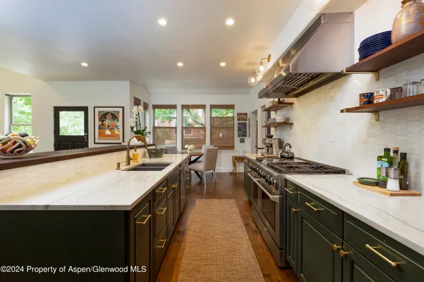 a kitchen with stainless steel appliances granite countertop a sink a stove and a wooden floors
